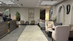 Eine moderne Lobby mit Empfangstresen, Sitzgelegenheiten und einem großen Wandkunstwerk.