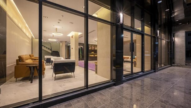 Eine moderne Hotelhalle mit Glaswänden, einer Rezeption und Sitzbereichen.