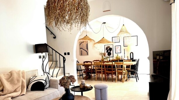 A modern living room with a sofa, coffee table, and ottoman, leading to a dining area with a table and chairs.