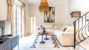 A modern living room with a sofa, coffee table, and a hanging light fixture.