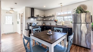 A modern kitchen with a central island, built-in appliances, and a dining area with blue chairs. - Tranquil Lakefront Farm Oasis ~ Pool ~ Scenic View<br>  (Bumpass)