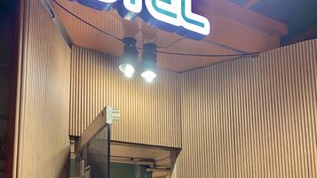 Interior de un hotel con un cartel llamativo que dice 'HOTEL', paneles de madera y un ventilador de techo.