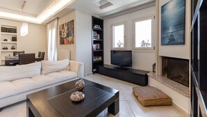 Een moderne woonkamer met een bank, salontafel, televisie, boekenkast en open haard.