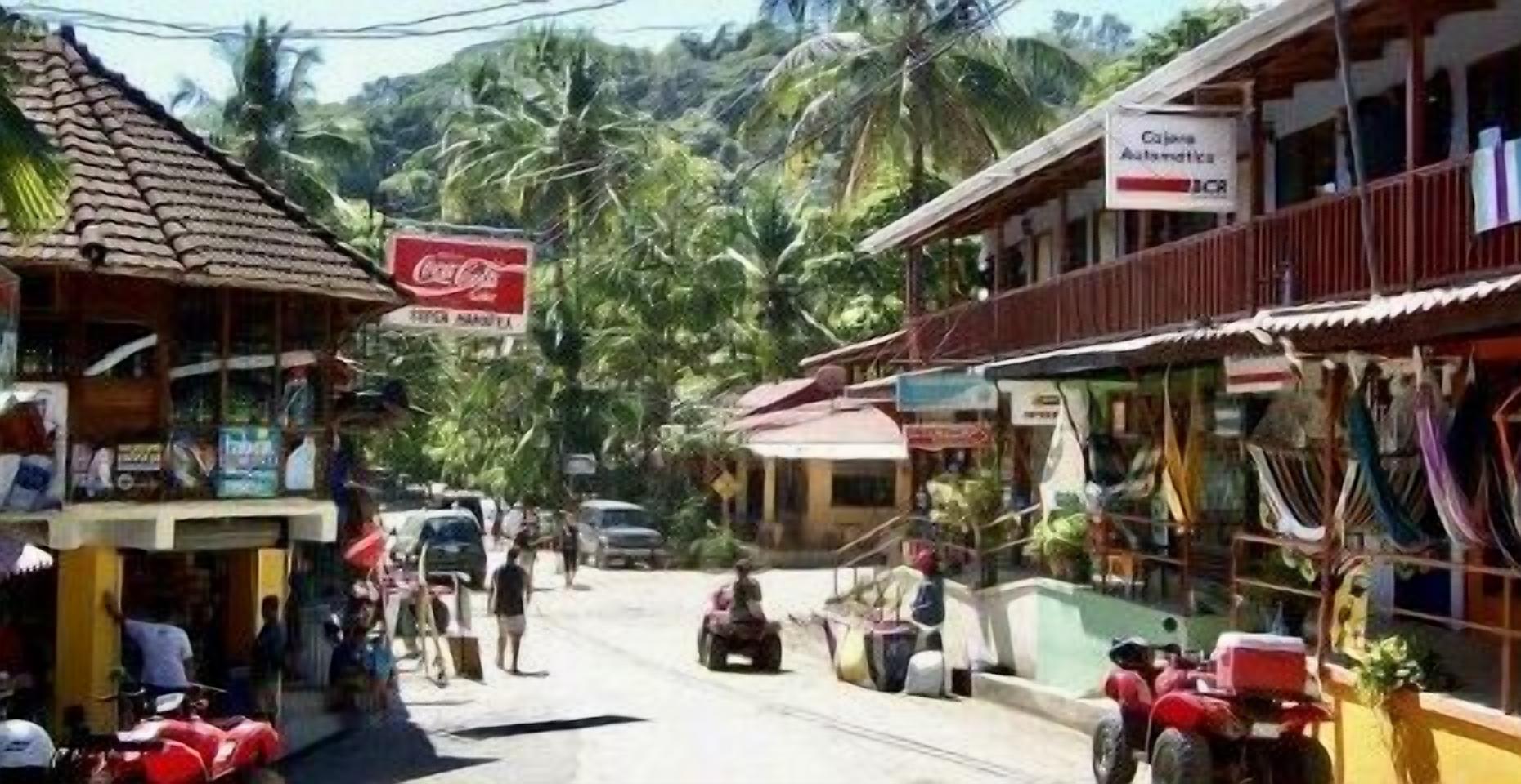 Vista de una calle con edificios, un anuncio de Coca-Cola y un letrero que dice 'Cajona Autentica'.