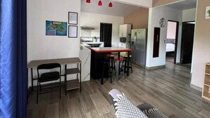 Un espacio habitable compacto con kitchenette, comedor y una pequeña zona de estar.