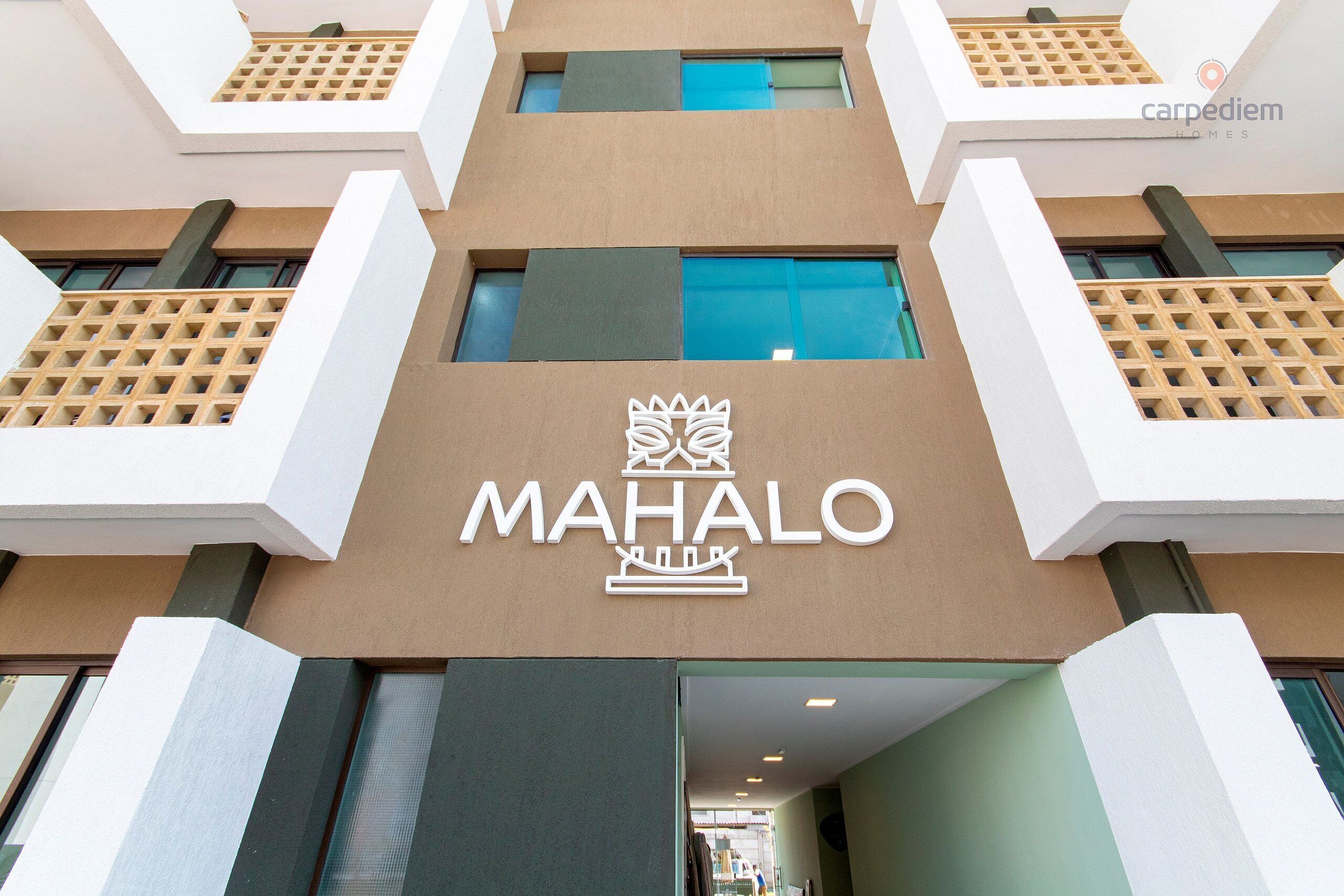 Um edifício com um destaque para o letreiro 'MAHALO' e design arquitetônico moderno.