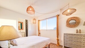 A bedroom with a bed, a bedside lamp, a dresser, a mirror, and a window with curtains. - Villa Zanzibar - 80m from the beach with pool (Mimizan)