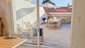 A room with a sliding glass door leading to an outdoor patio area. The patio has a wooden deck, a table with chairs, and a hammock. - Villa Zanzibar - 80m from the beach with pool (Mimizan)
