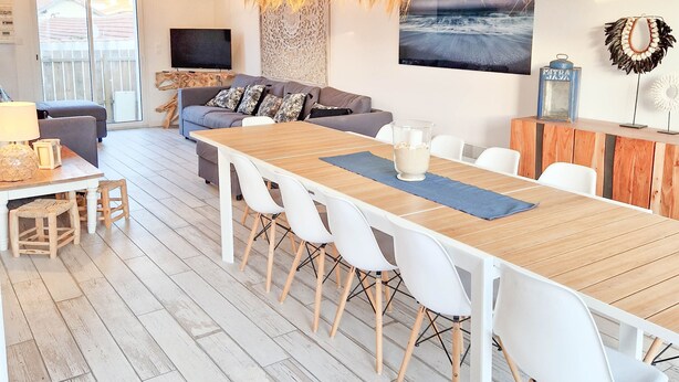 A modern living room with a sofa, dining table, and hanging light fixtures. - Villa Zanzibar - 80m from the beach with pool (Mimizan)