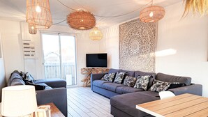 A modern living room with a grey sofa, a wooden dining table, and wicker pendant lights. - Villa Zanzibar - 80m from the beach with pool (Mimizan)