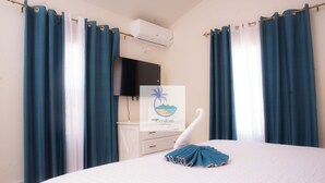 A hotel room with a bed, a TV mounted on the wall, and a sign with a palm tree and waves.