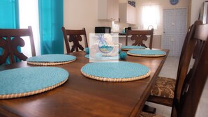 A dining table with four blue placemats, wooden chairs, and a central decorative item.