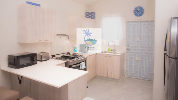 A compact kitchen with a microwave, toaster, gas stove, and a sink.