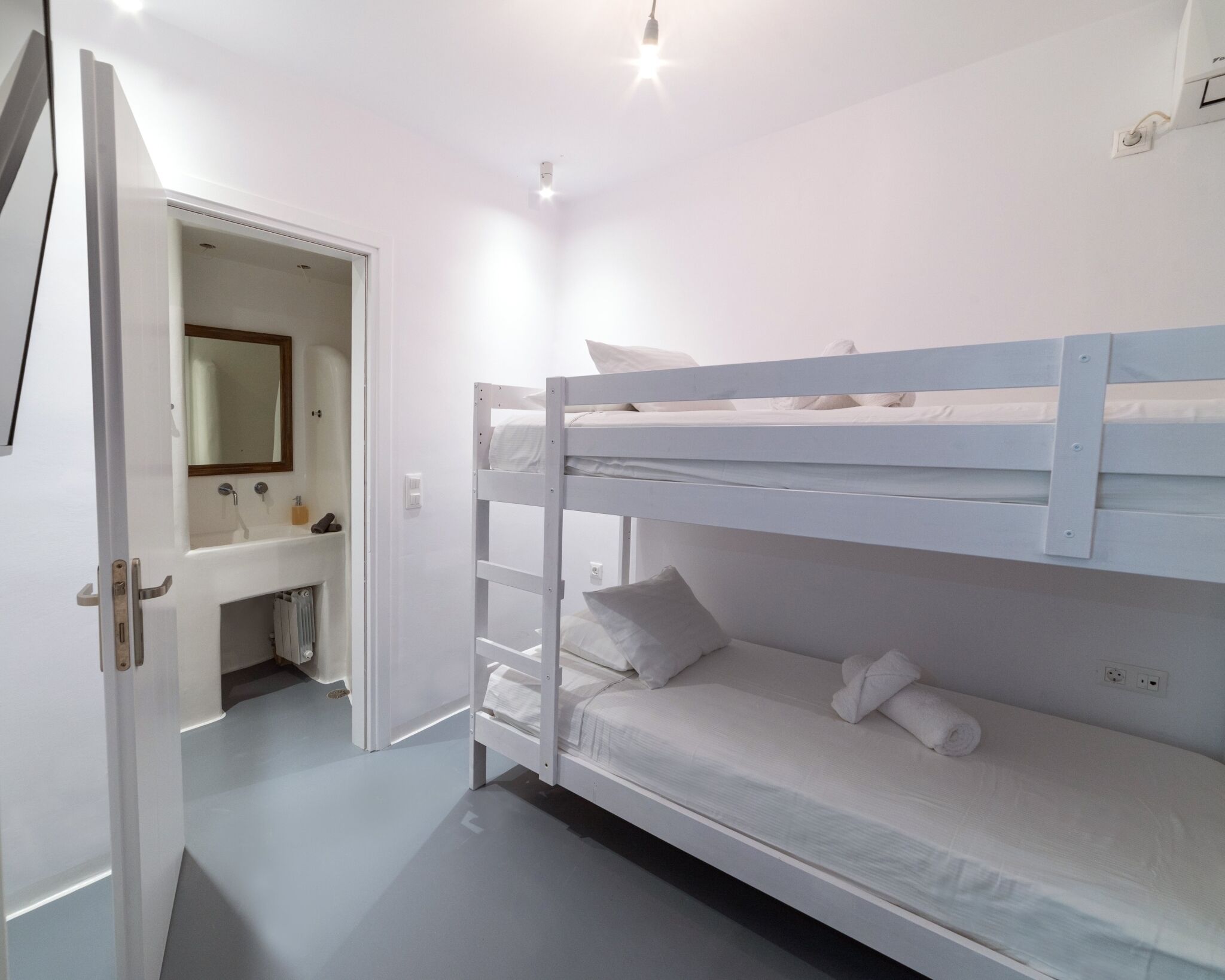 A bunk bed room with a white door, a mirror, and a sink.