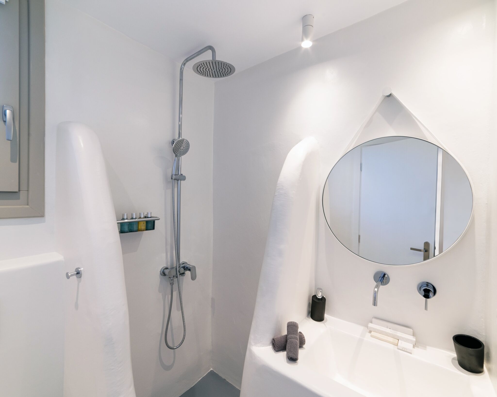 A modern bathroom with a shower, a round mirror, and a white sink.
