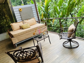 Relax in a serene garden setting with a comfortable sofa and wicker chair.