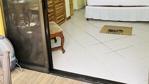 Una habitación de hotel con cama, ventilador de techo, mesita de noche, lámpara y un cabecero decorativo.