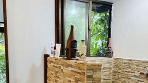 Un baño con pared de piedra, un inodoro y una ventana con vistas a la vegetación.