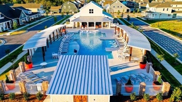 A swimming pool with lounge chairs and a covered area, surrounded by houses. - Family Friendly House - Resort Style Amenities & Baby Gear (Beaufort)