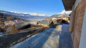A balcony with a view of snow-capped mountains and a village below.