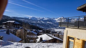 A snow-covered mountain landscape with a modern building featuring large windows and a balcony.