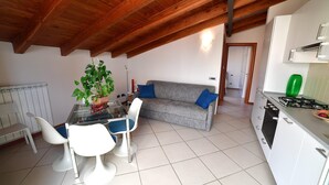 Une cuisine moderne avec des meubles blancs, une cuisinière à gaz et un coin repas comprenant une table en verre et des chaises blanches.