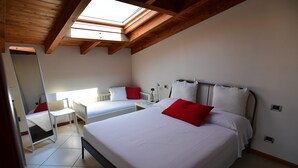 Une chambre avec deux lits, une lucarne et un sol carrelé de carreaux blancs.