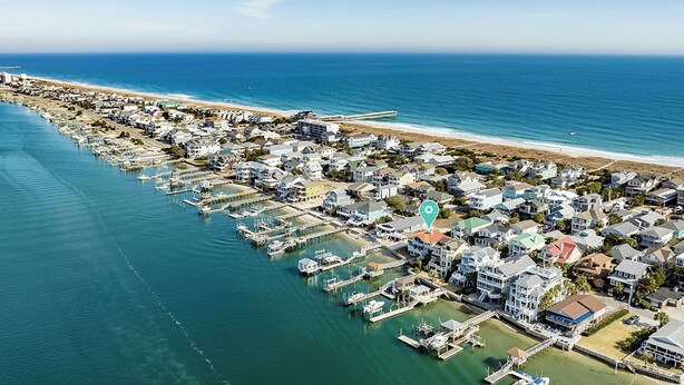 Vue aérienne d’une zone résidentielle côtière, avec des maisons, des quais et une plage.
