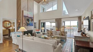 Un salon spacieux doté d’une cheminée, de grandes fenêtres et offrant une vue sur la mer.