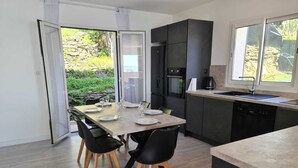 Een moderne keuken met een eethoek, met een grote tafel voor zes personen, een ingebouwde oven en een vaatwasser.