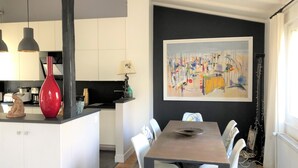 A modern kitchen with white cabinets, a red vase, and a dining area with a table and chairs. - 500 m from Roland Garros stadium, apartment with terrace (6-8 people) (Boulogne-Billancourt)