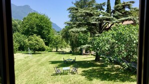 A view of a well-maintained garden with a lawn, several trees, and a seating area with chairs and tables. - Cervano Ecli: apartment for 5 with original fireplaces from 1886 (Lombardia)