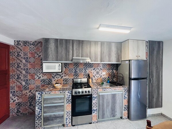 A compact kitchen with a microwave, stove, oven, and refrigerator.