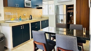 A modern kitchen with dark cabinets, a stainless steel refrigerator, a built-in oven, and a granite countertop. - Meson del Capitan Apartments (Mazatlán)