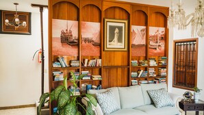 A living room with a sofa, bookshelves, and a large plant. - Meson del Capitan Apartments (Mazatlán)