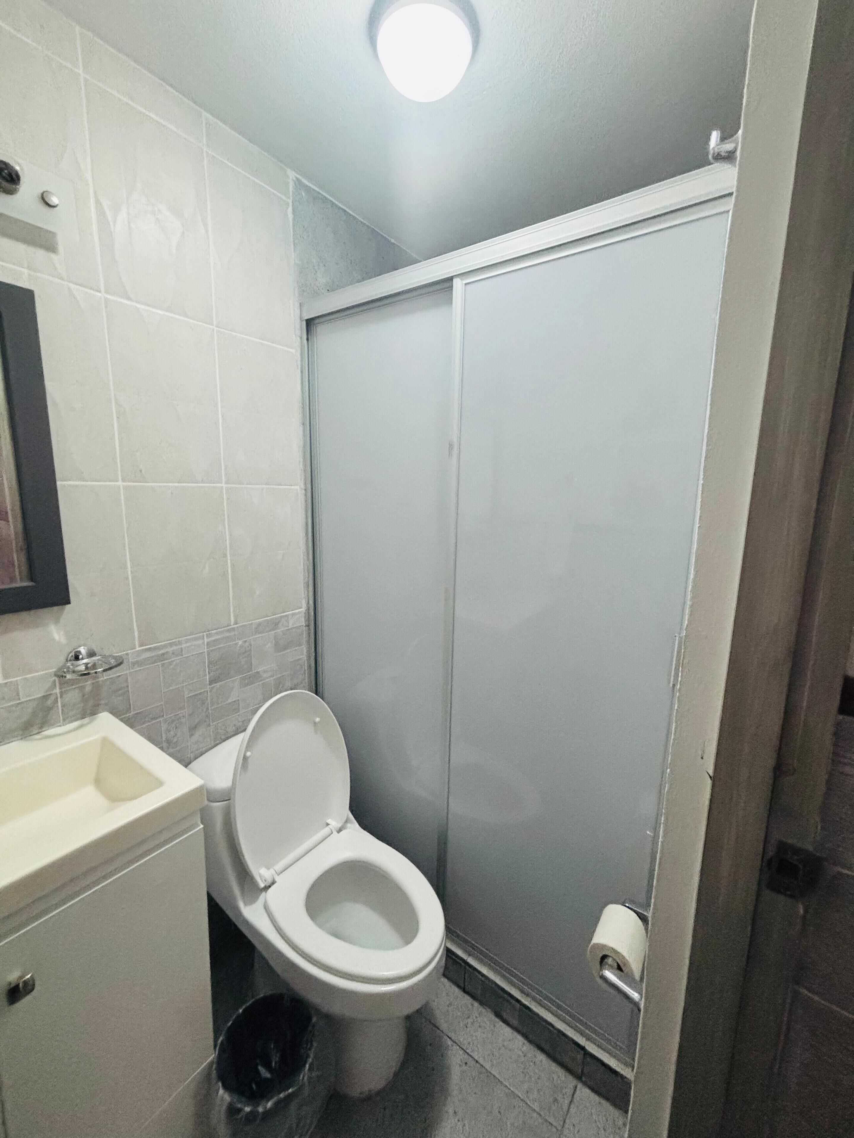 A bathroom with a toilet, sink, and shower stall.