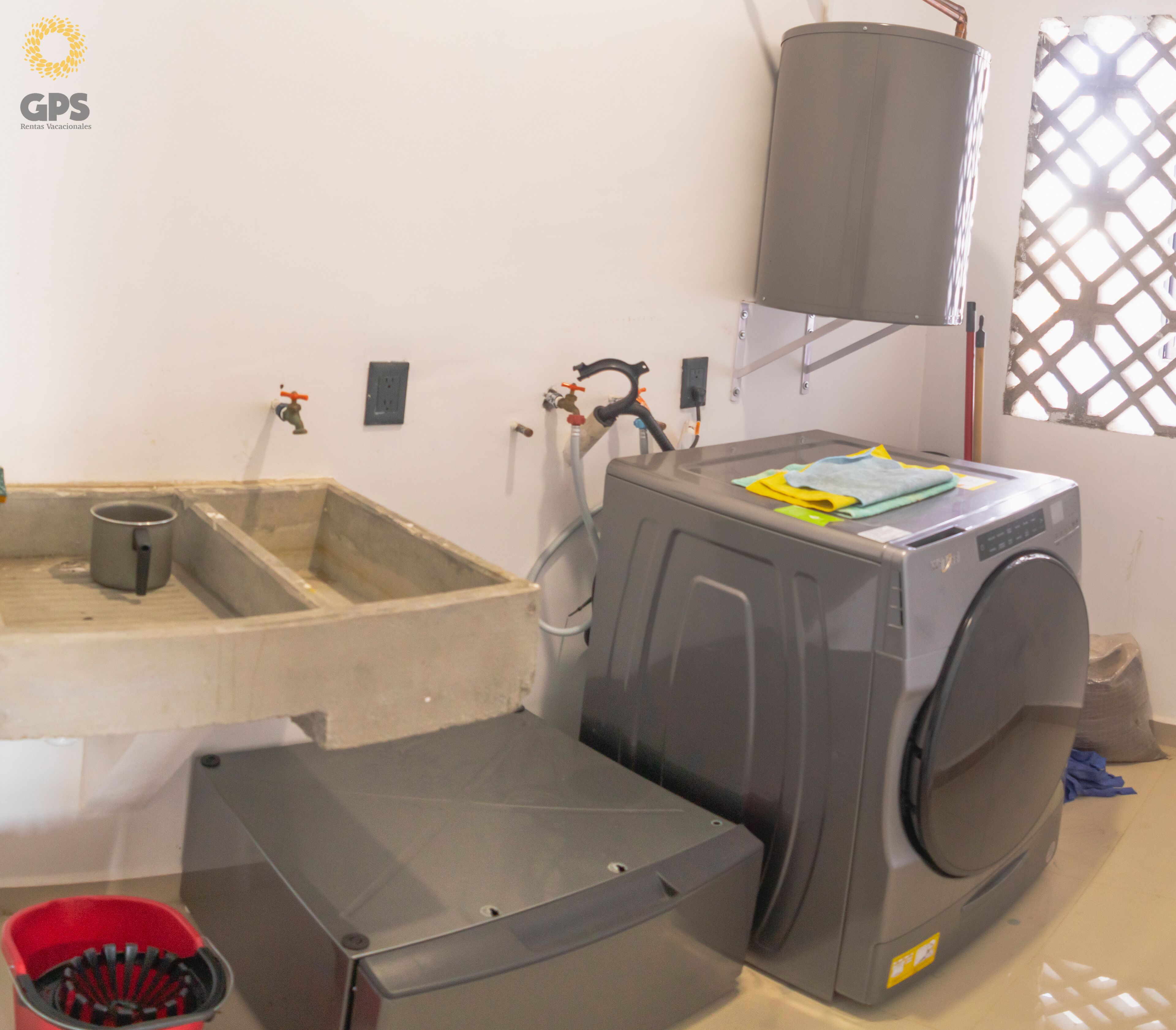 A laundry area with a washing machine, a sink, and a drying rack.
