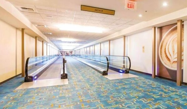 A long, empty corridor with an escalator in the center, leading to a higher level.