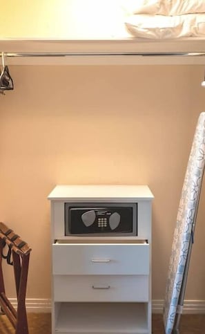 A white bedside table with a radio, a drawer, and a small shelf.