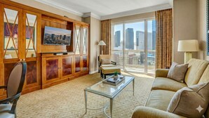 A hotel room with a city view, a large wooden entertainment unit, a sofa, a coffee table, and a chair. - MGM Signature | 11th Floor 1BR | Strip View | No Resort Fee (LAS VEGAS)