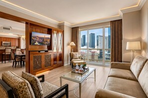 A modern living room with a city view, a dining area with a wooden cabinet, and a kitchen with a microwave.