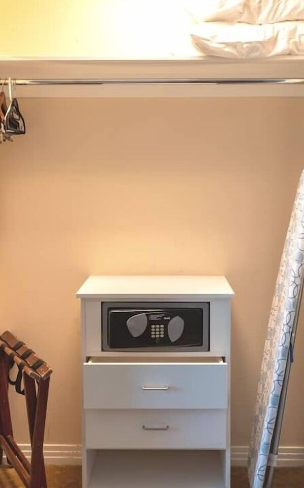 A small white bedside table with a radio, a drawer, and a hanging coat hook.