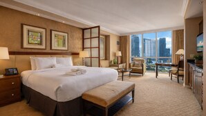 Une chambre d’hôtel avec un grand lit, un bureau, une chaise, un banc et une vue sur les toits de la ville.