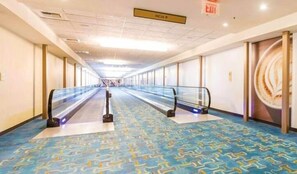 A long, empty corridor with escalators, patterned carpet, and a sign indicating the exit.