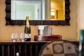 A bar area with a bottle of champagne, two glasses, and a large metal container on a wooden counter.