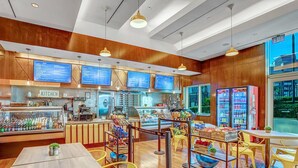 Un restaurant moderne avec des lambris en bois, un espace cuisine et un coin salon avec des chaises jaunes.