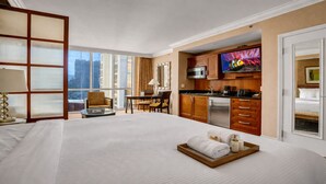 Habitación de hotel con una cama grande, comedor, cocina y televisor.