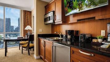 A modern kitchen with a large window, a flat-screen TV, and a city view.