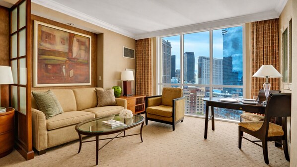 A spacious living room with a large window offering a city view, a comfortable sofa, a coffee table, and a dining area with a table and chairs.