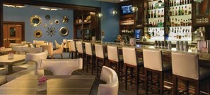 A bar area with multiple seating options, a well-stocked bar, and decorative wall elements.